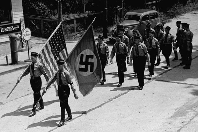 American Nazi party members march while carrying Nazi and American flags near Camp Siegfried, Long Island.